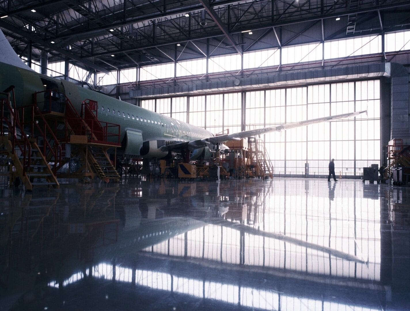 A large airplane in an airport hangar with its wings open.